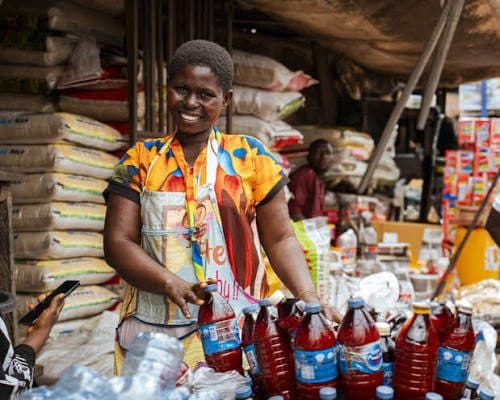 A smiling market trader at her stall in a Nigerian market